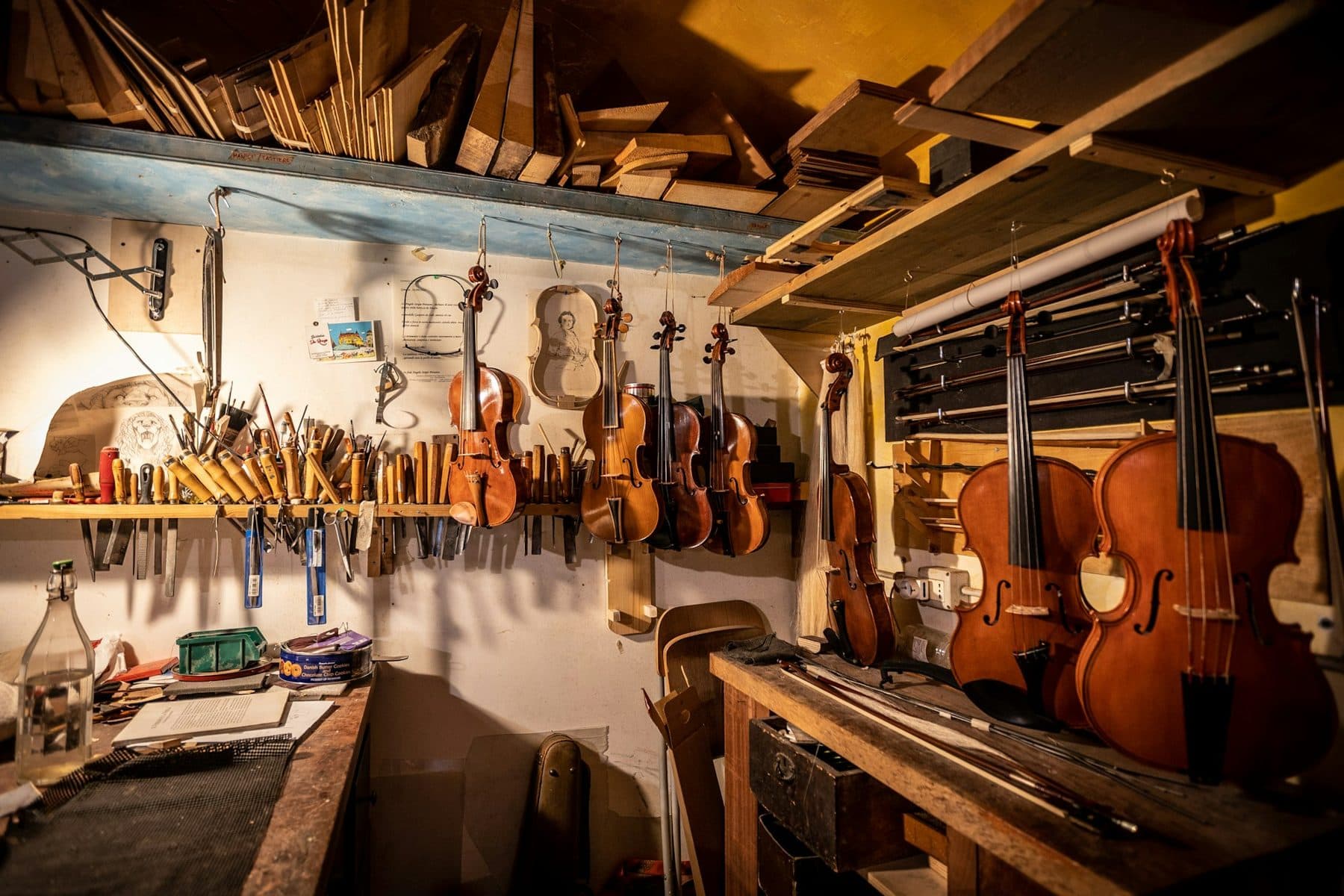 Violins hanging above a luthier's workbench